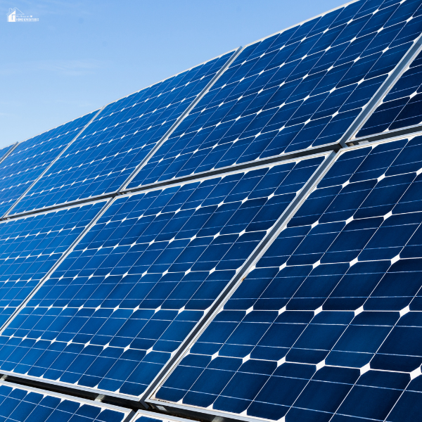 A close-up of clean, blue solar panels angled under sunlight against a clear sky backdrop.