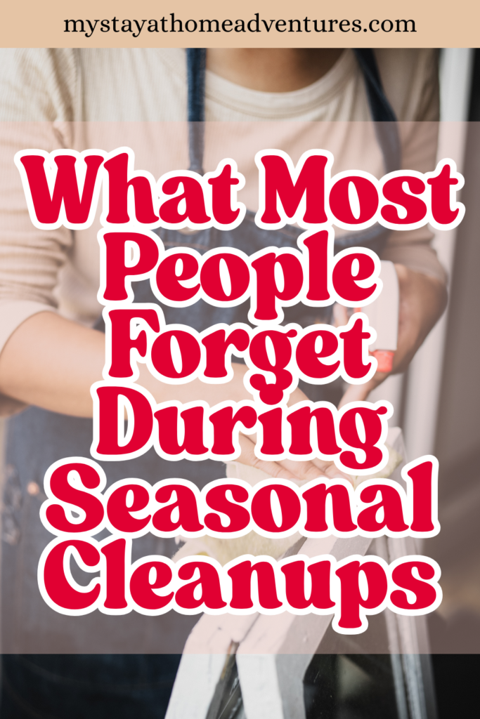 A person wearing an apron holds a cleaning brush and scrub pad in front of a window, preparing for seasonal home maintenance tasks.