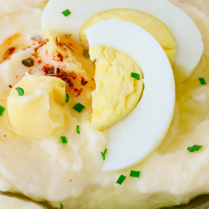 A bowl of creamy Puerto Rican mashed potatoes with eggs, topped with sliced hard-boiled egg, butter, and herbs—an authentic Caribbean side dish perfect for holiday meals and comfort food lovers.