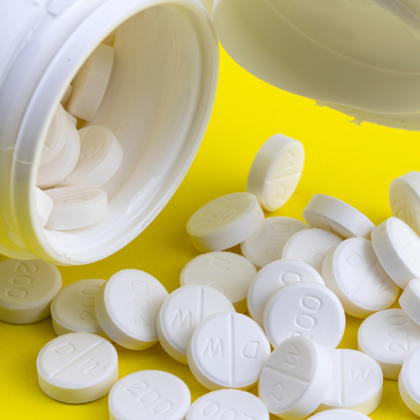 A white bottle spills round white tablets across a bright yellow background, representing allergy medication.