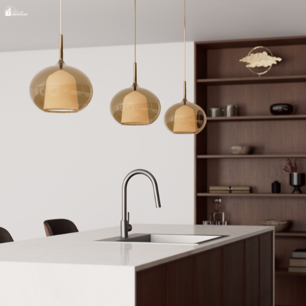 A modern kitchen with three gold pendant lights hanging over a white island countertop with a built-in sink.