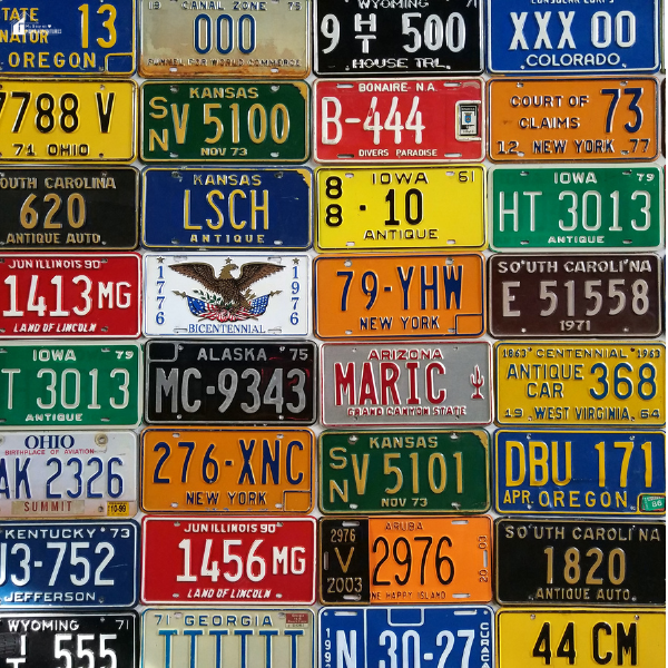 A colorful display of vintage and state license plates arranged in a grid, showcasing the variety car enthusiasts enjoy collecting.