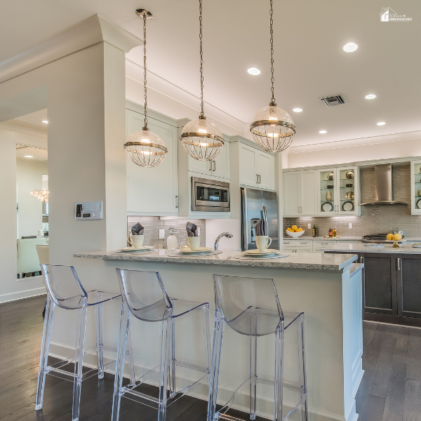 A bright kitchen featuring glass globe gold pendant lights above a breakfast bar with clear acrylic stools.
