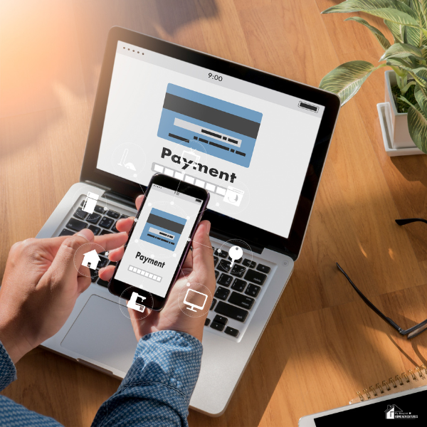 A person processing an online payment transaction with the use of a phone and a laptop.