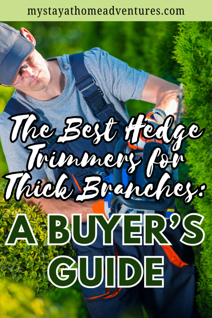 A person in protective gear uses a hedge trimmer on thick green bushes in a sunny backyard.