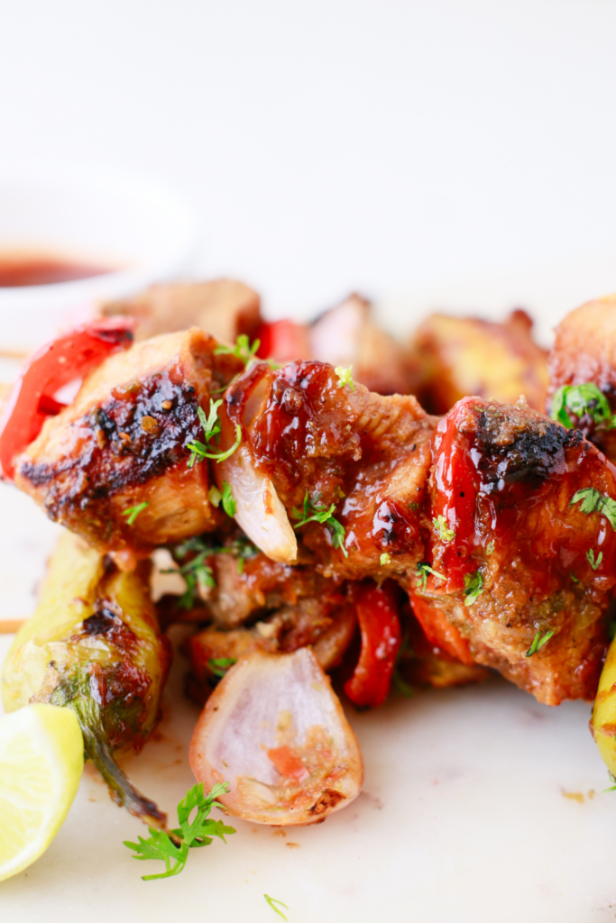 Puerto Rican Pinchos de Carne served with onions, red peppers, shishito peppers, and a wedge of lime.