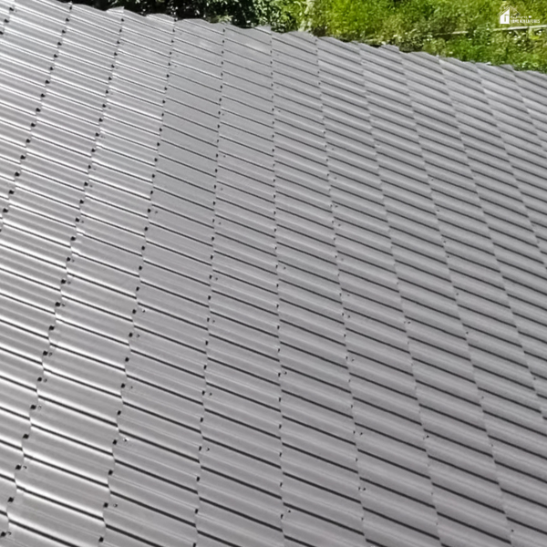 An image of a gray flat roof with evenly installed roofing sheets.