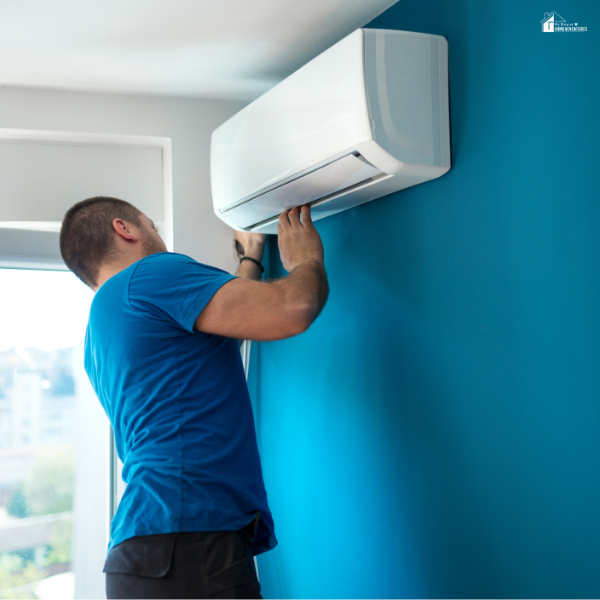 A man performs maintenance on a wall-mounted air conditioning unit in a modern home.