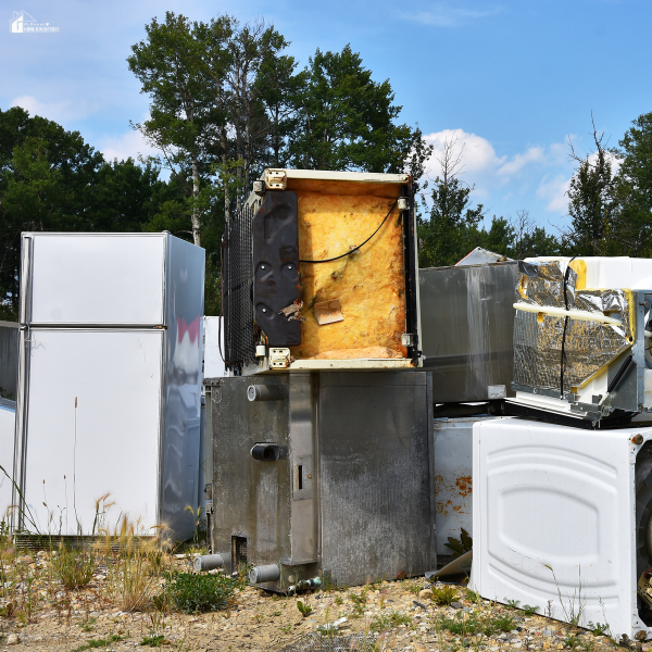 A pile of broken refrigerators and appliances discarded outdoors, showing items beyond repair.