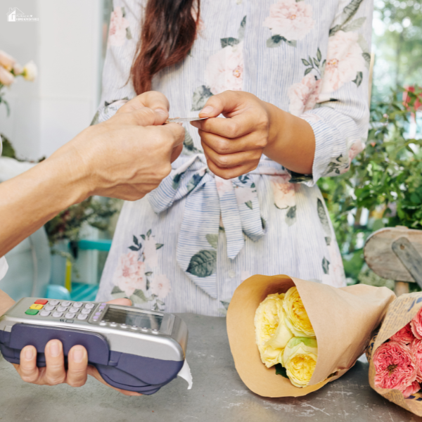 A customer paying for a bouquet of yellow roses with a credit card at a florist counter.