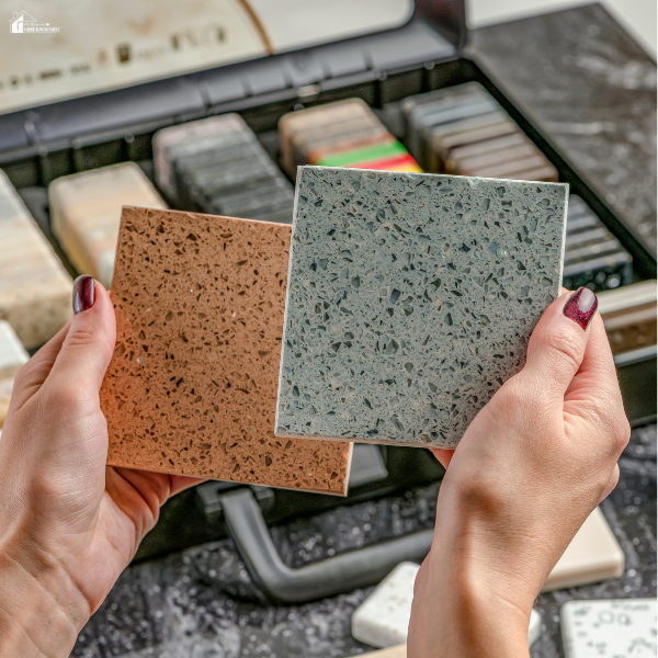 A person holding two different countertop or tile samples while comparing options during a home renovation project.