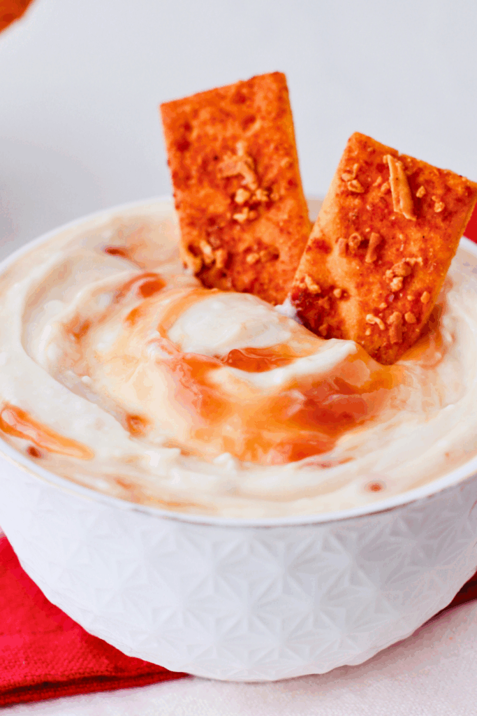 White bowl filled with creamy Puerto Rican guava dip topped with swirls of guava and served with crackers, a tropical Caribbean appetizer perfect for parties.