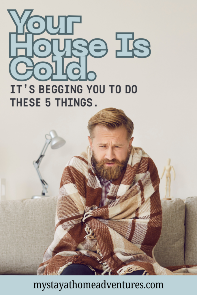 Man wrapped in a blanket sitting on a couch, looking cold in a home setting.