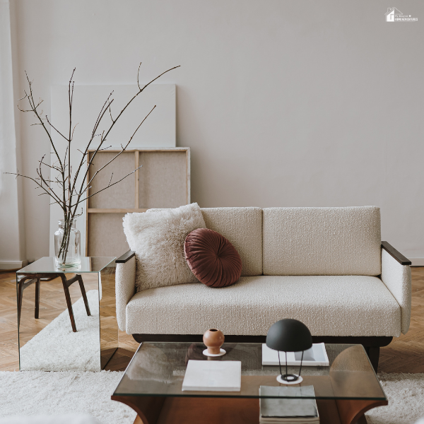 A modern living room with a cozy cream-colored sofa, accent pillows, and a glass coffee table creating a clean, minimal design.