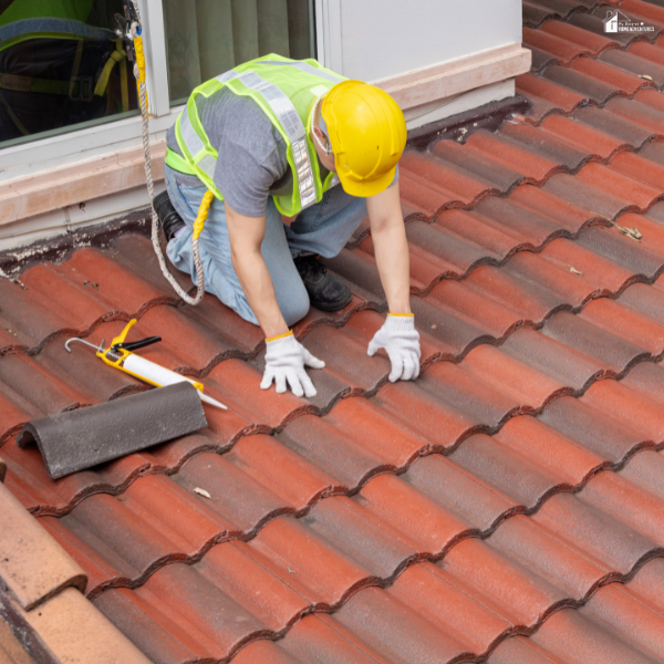 A professional in safety gear inspects and repairs clay roof tiles on a residential home.