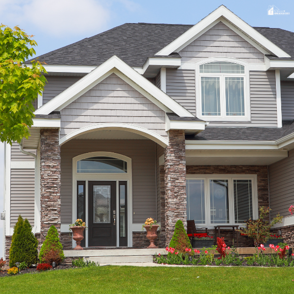 A modern suburban home with a landscaped front yard featuring shrubs, flowers, and decorative planters by the entrance.