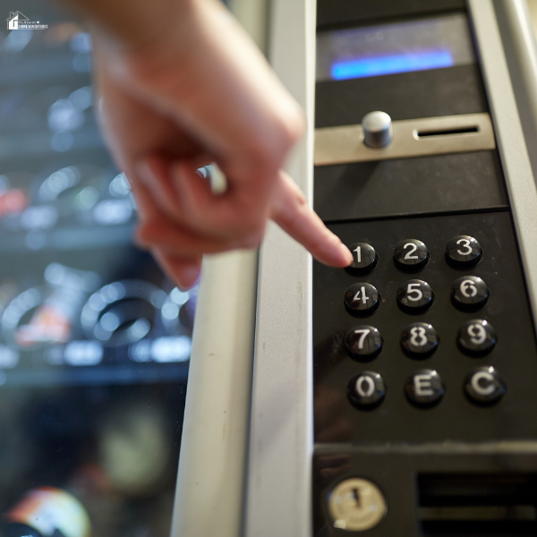 A hand pressing buttons on a vending machine keypad to make a purchase.