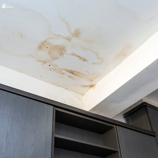 A stained ceiling with visible water damage above kitchen cabinets, indicating a possible roof or plumbing leak.