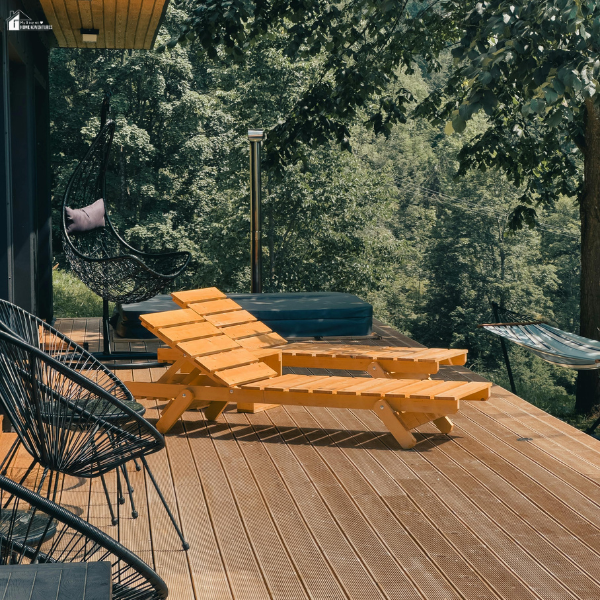 A contemporary deck in a wooded setting featuring wooden lounge chairs, black woven chairs, and a hammock for relaxation.