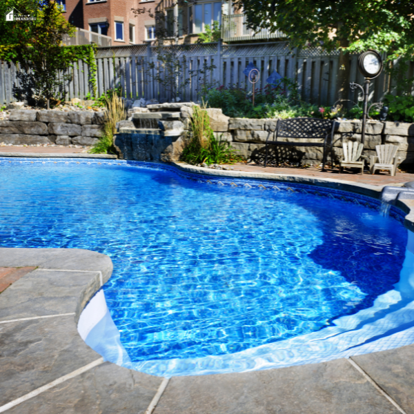 A backyard lagoon pool with stone accents, waterfall feature, and seating area nearby.