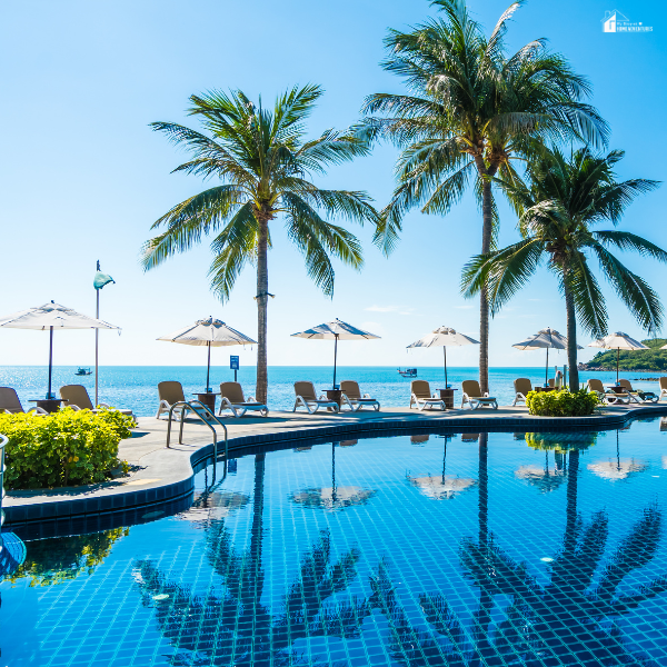 A resort-style pool by the ocean with palm trees and lounge chairs, highlighting pool equipment exposed to salty coastal air.