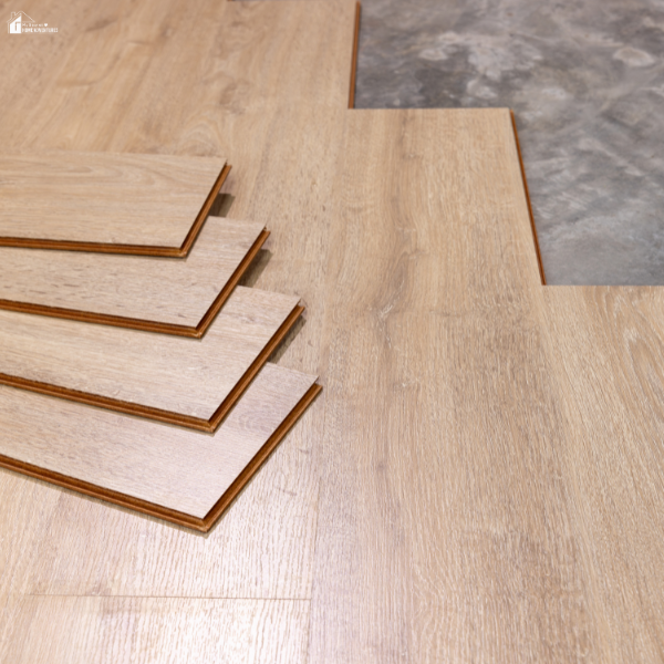 Wooden laminate planks are laid out on a concrete floor, ready for installation as modern flooring.