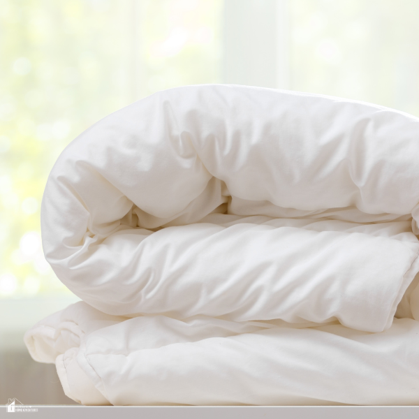 A neatly folded white percale duvet cover placed on a bright surface.