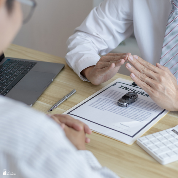 A person discussing car insurance and warranty details with an agent at a desk.