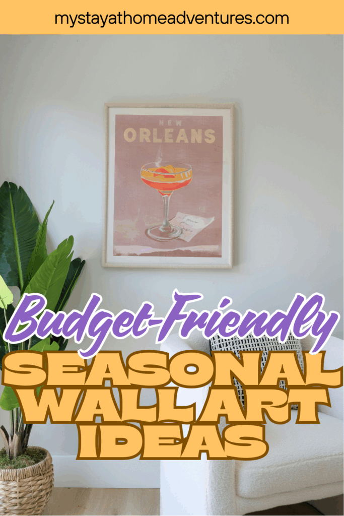 A framed cocktail-themed print displayed on a neutral wall above a chair with a plant nearby, showcasing seasonal wall art.