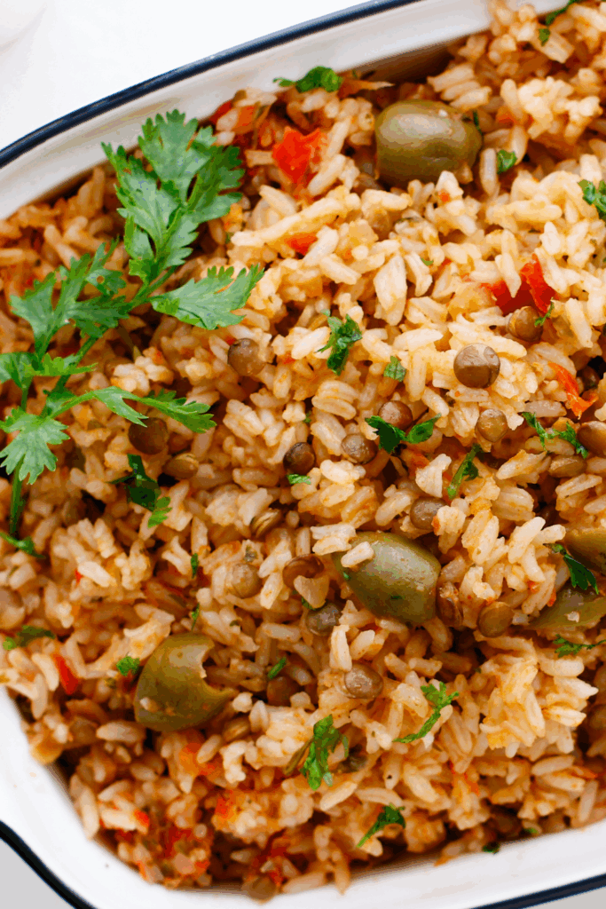 Detailed top view of Puerto Rican rice showing fluffy grains, green olives, and fresh herbs in a serving dish.