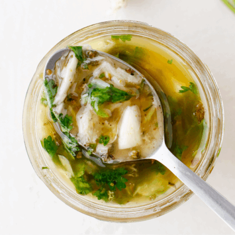 A spoonful of Puerto Rican mojo sauce showing chunks of garlic and herbs.