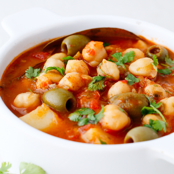 A close-up of Puerto Rican stewed chickpeas simmered in tomato sauce with green olives and fresh cilantro.