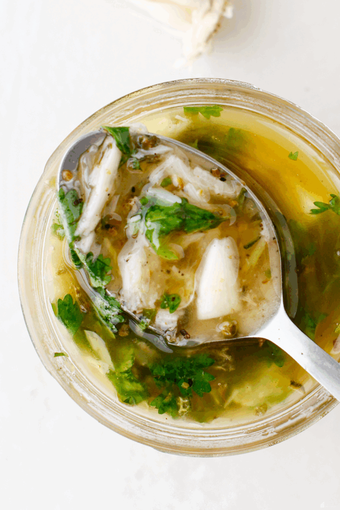 A spoonful of Puerto Rican mojo sauce showing chunks of garlic and herbs.