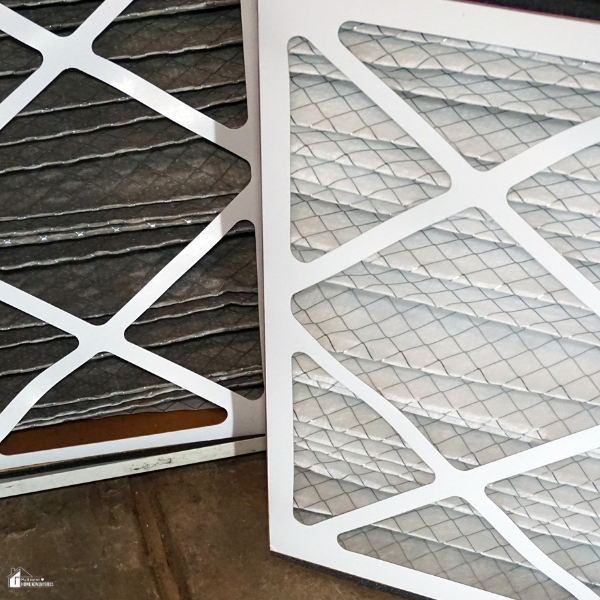 Two furnace filters, one clean and one dirty, are placed side by side for comparison.