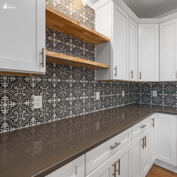 A modern kitchen with white cabinets, open wooden shelves, and black-and-white patterned terracotta backsplash tiles.