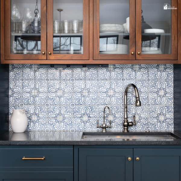 A blue kitchen with wooden upper cabinets and a blue-and-white patterned terracotta tile backsplash behind the sink.