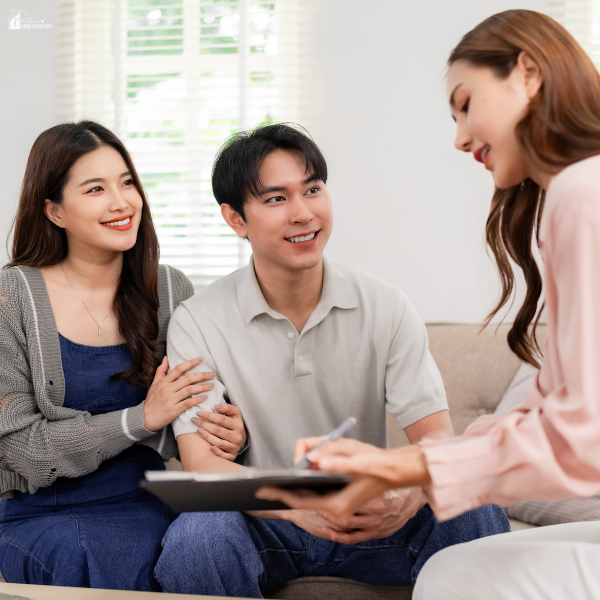 A couple smiles while speaking with a home expert in a bright living room.