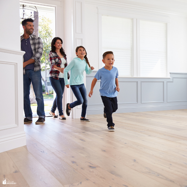 Parents and two children walk excitedly into a new empty home with natural light.