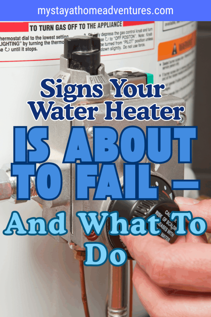 A close-up of a person's hand turning the temperature dial on a home water heater.