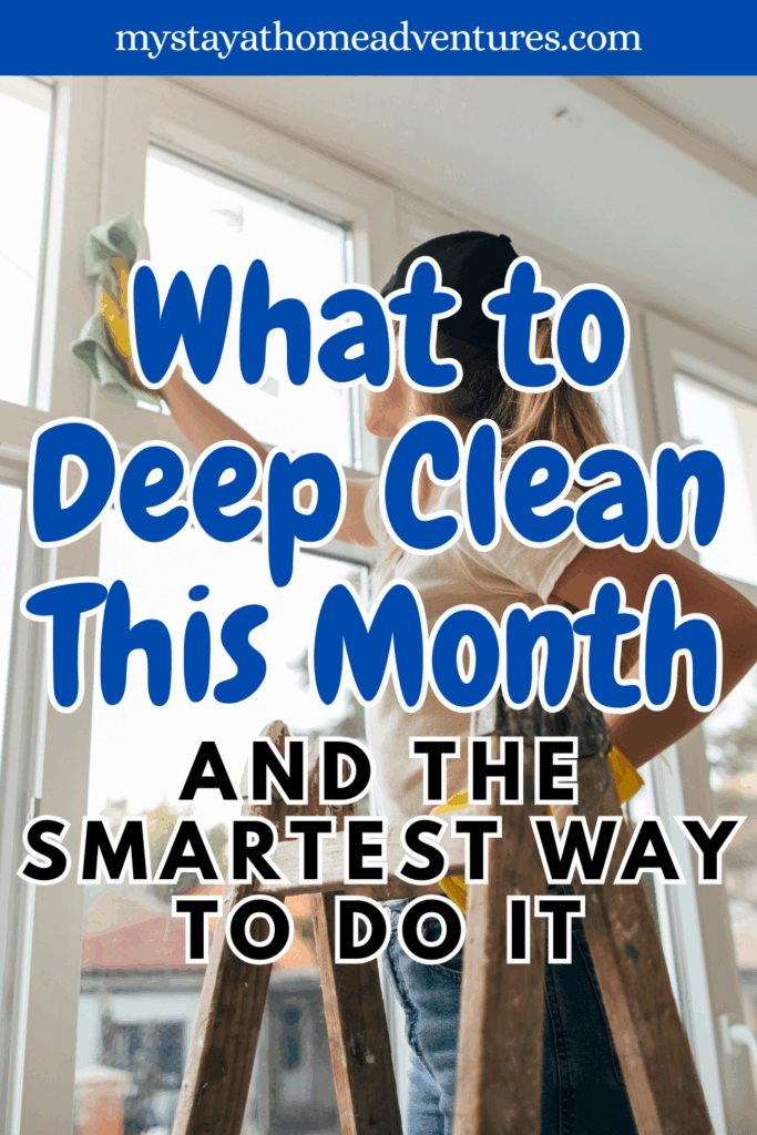 A person standing on a ladder, deep cleaning a large window with a green cloth while sunlight shines through the glass.