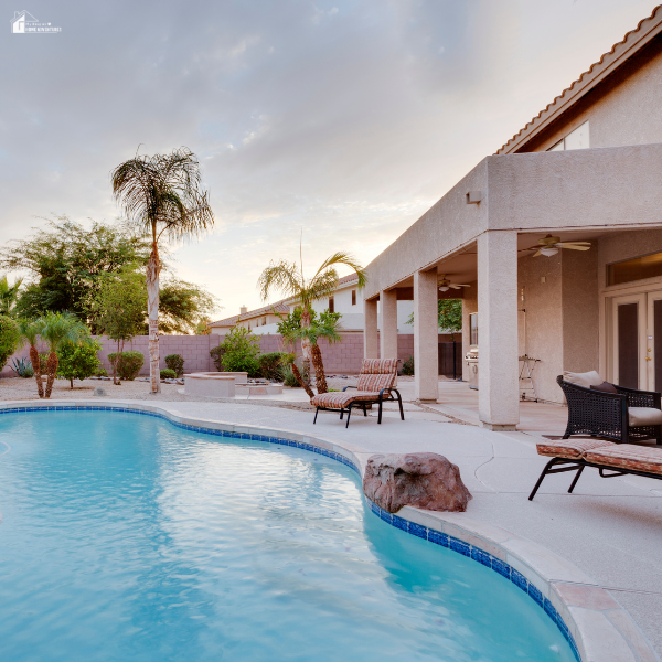 A serene backyard pool surrounded by lounge chairs and palm trees, ideal for creating a relaxing stay-at-home oasis.