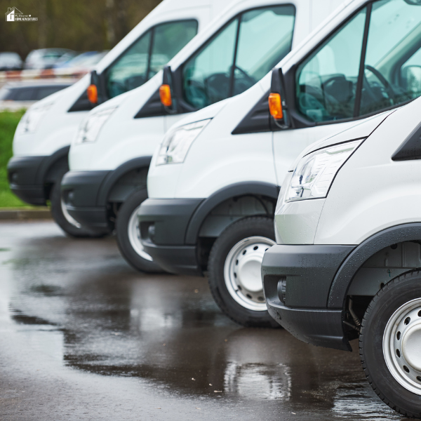 A row of white transport vans parked in a lot, representing a professional moving fleet.
