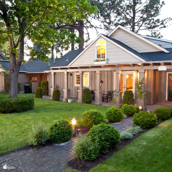 A cozy home with warm exterior lighting, trimmed shrubs, and a clean garden walkway that shows how outdoor improvements reduce indoor mess.