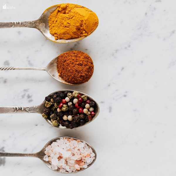 An overhead view of spoons filled with colorful spices and herbs that highlight the vibrant ingredients used in Mediterranean cooking.