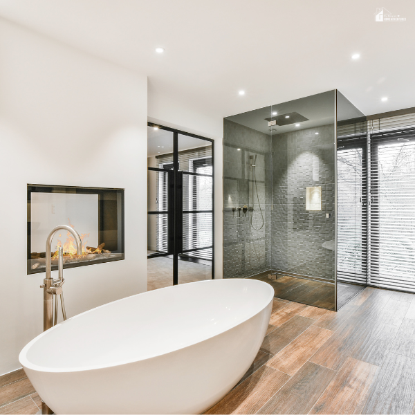 Modern bathroom with a freestanding tub, wood-look floors, and a glass shower enclosure near large windows.