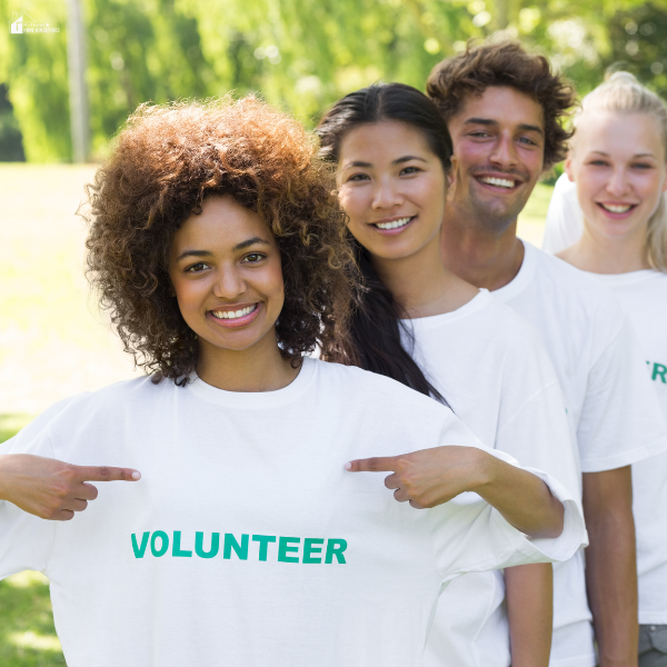 A group of teens wearing volunteer shirts smiles together outdoors as they gain experience for future career paths.