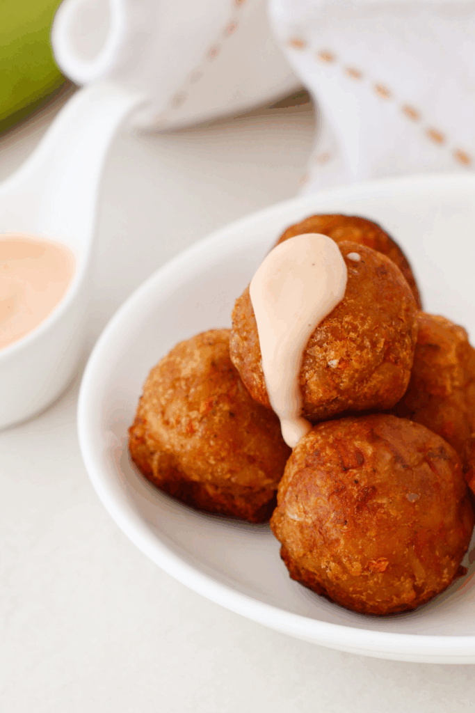 A close-up of mofongo balls with one topped with a dollop of mayo ketchup sauce, showcasing the crispy texture.