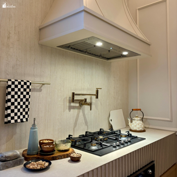 A sleek gas stove setup with modern fixtures, under a white range hood in a minimalist kitchen.