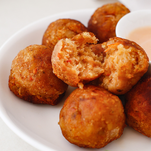A mofongo ball split in half revealing a soft, seasoned mashed plantain interior with colorful bits of garlic and onion.