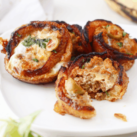 Plate of multiple plantain cups, one partially eaten to reveal the seasoned ground beef and olive filling.